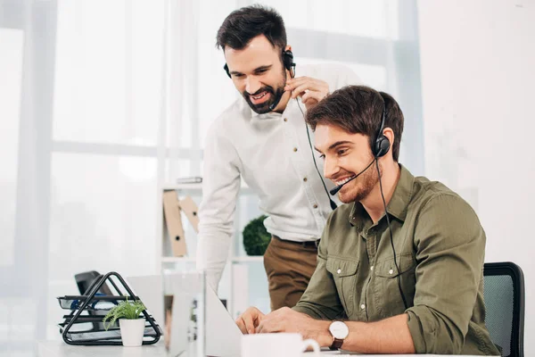 Lächelnde Callcenter-Betreiber blicken im Büro auf Laptop-Bildschirm — Stockfoto