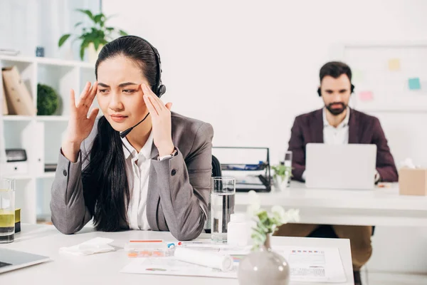 Sick call center operator touching head in office — Stock Photo