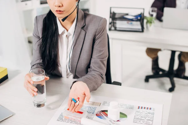 Ausgeschnittene Ansicht einer Betreiberin mit Tabletten und einem Glas Wasser — Stockfoto