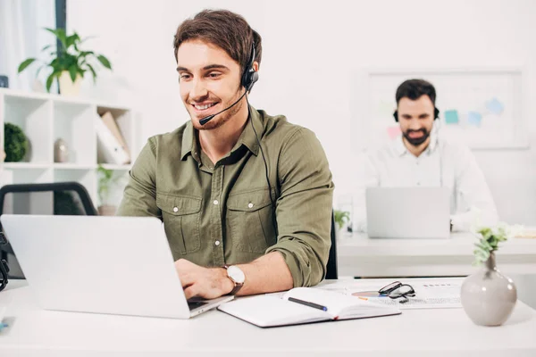 Selective focus of young operator in headset working in modern call centre — Stock Photo