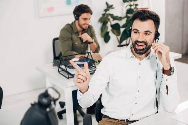 Cheerful male operator using headset and talking in call centre — Stock Photo