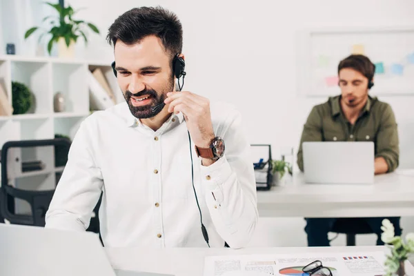 Operatore maschile che utilizza auricolari mentre lavora in call center — Foto stock