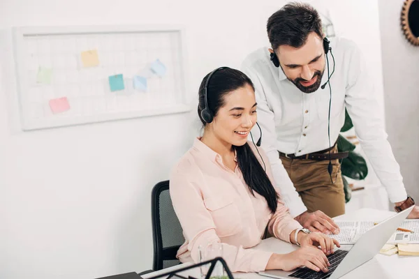 Femme gestionnaire tapant au clavier de l'ordinateur portable près de collègue masculin dans le bureau — Photo de stock