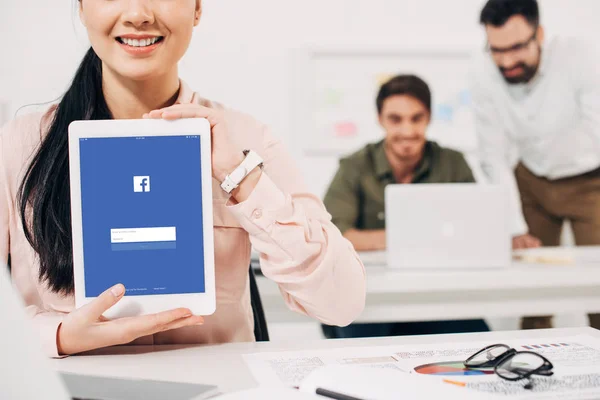 Cropped view of female manager showing digital tablet with facebook app — Stock Photo