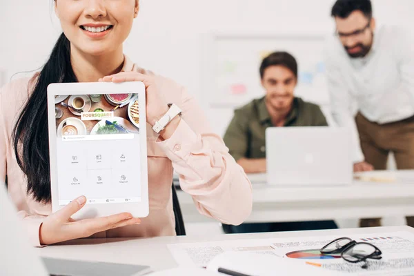 Cropped view of female manager showing digital tablet with foursquare app — Stock Photo