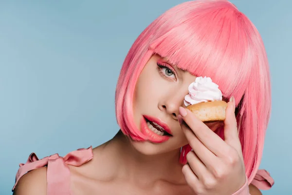 Sinnliche junge Frau in rosa Perücke posiert mit leckeren Cupcake isoliert auf blau — Stockfoto