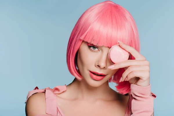 Attraktives Mädchen in rosa Perücke posiert mit Macaron isoliert auf blau — Stockfoto