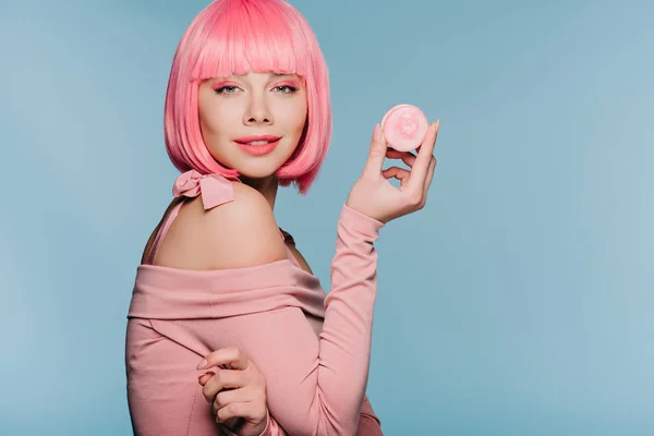 Belle fille en perruque rose posant avec macaron savoureux isolé sur bleu — Photo de stock