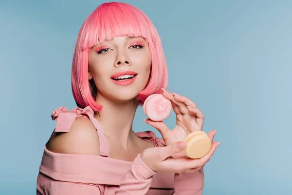 Attractive stylish girl in pink wig posing with macarons isolated on blue — Stock Photo