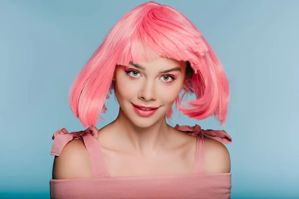 Hermosa chica feliz posando en peluca rosa aislado en azul - foto de stock