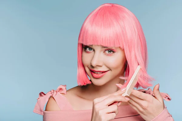 Menina sorrindo pentear o cabelo rosa isolado no azul — Fotografia de Stock