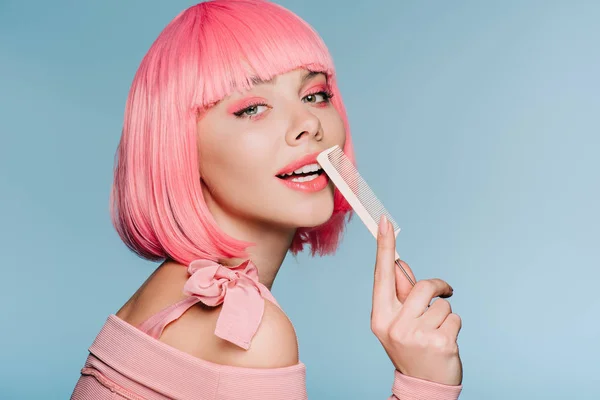 Menina sensual em peruca rosa posando com pente de cabelo isolado em azul — Fotografia de Stock