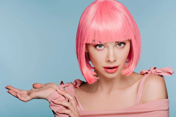 Beautiful shocked girl in pink wig posing with shrug gesture isolated on blue — Stock Photo