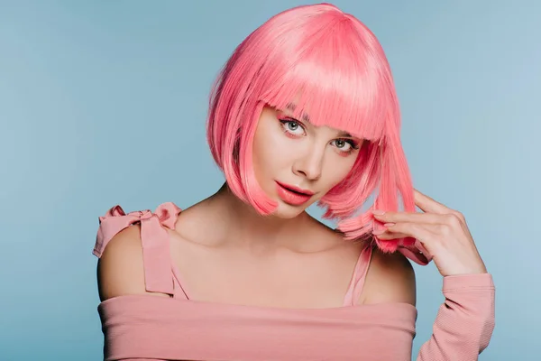 Encantadora chica posando en peluca rosa para disparar de moda aislado en azul - foto de stock