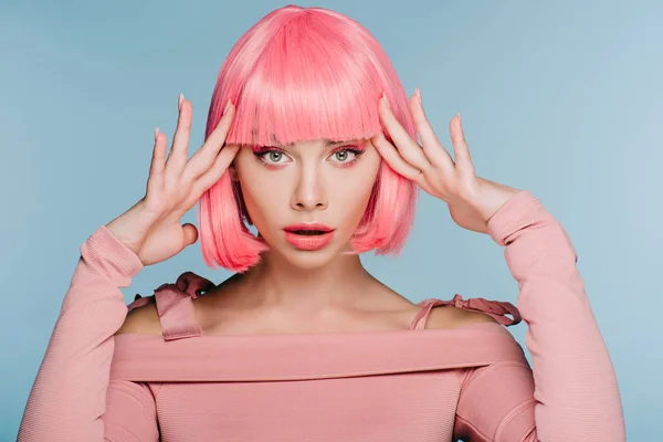 Приваблива шокована дівчина жестикулює і позує в рожевій перуці ізольована на синьому — стокове фото