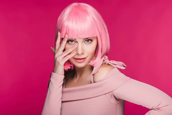 Красива молода жінка жестикулює і позує в рожевій перуці, ізольована на рожевому — стокове фото