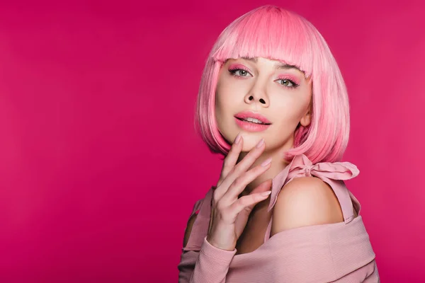 Atractiva chica elegante gesto y posando en peluca rosa, aislado en rosa - foto de stock