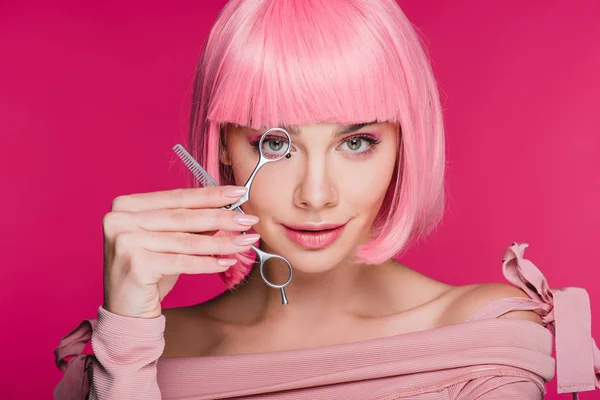 Sensual girl with pink hairstyle looking through scissors isolated on pink — Stock Photo