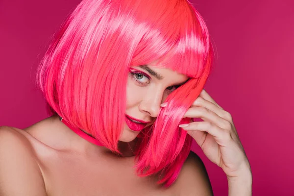 Модная обнажённая девушка позирует в неоновом розовом парике, изолированная на розовом — стоковое фото