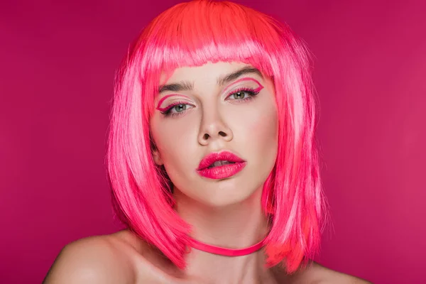 Hermosa chica con maquillaje de moda posando en peluca de neón rosa, aislado en rosa - foto de stock