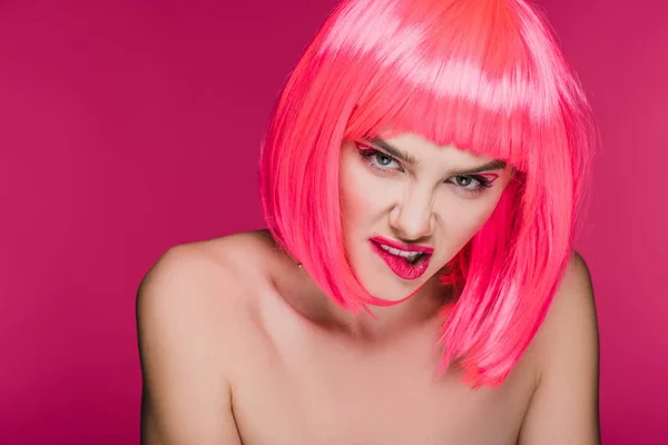 Chica agresiva desnuda en neón peluca rosa morder labio, aislado en rosa - foto de stock