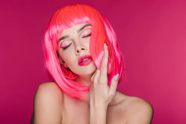 Chica tierna desnuda con los ojos cerrados posando en peluca de neón rosa, aislado en rosa - foto de stock