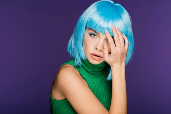 Чувственная молодая женщина позирует в голубом парике и зеленой водолазке, изолированная на фиолетовый — стоковое фото