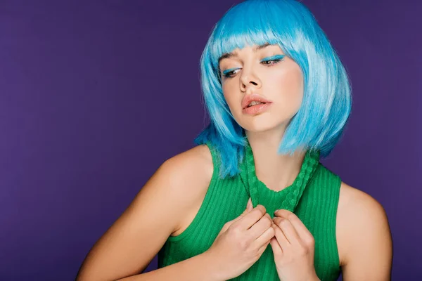 Привлекательная стильная девушка позирует в голубом парике и зеленой водолазке, изолированная на фиолетовый — стоковое фото