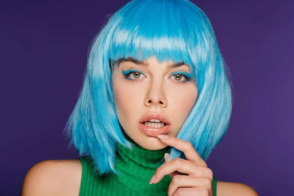 Sensual joven mujer en azul peluca tocando labio, aislado en púrpura — Stock Photo