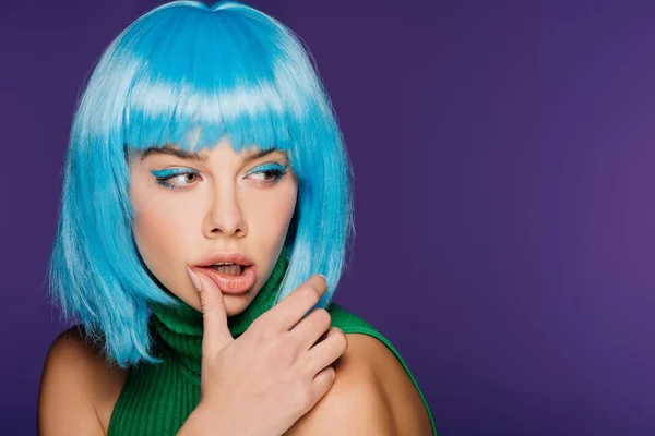 Attraktives sinnliches Mädchen mit blauer Perücke, das die Lippe berührt, isoliert auf lila — Stockfoto