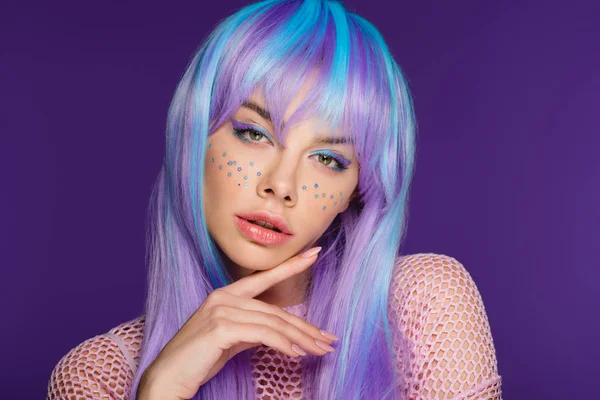 Belle fille élégante posant en perruque violette avec des étoiles sur le visage, isolé sur violet — Photo de stock