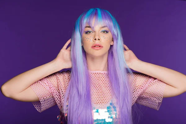 Pretty fashionable girl posing in violet wig with stars on face, isolated on purple — Stock Photo