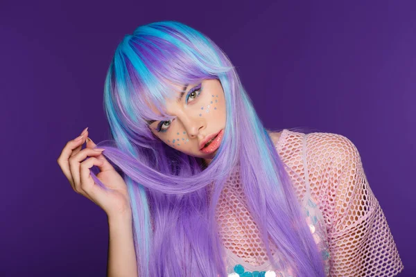 Bella ragazza affascinante in posa in parrucca viola con stelle sul viso, isolato su viola — Foto stock