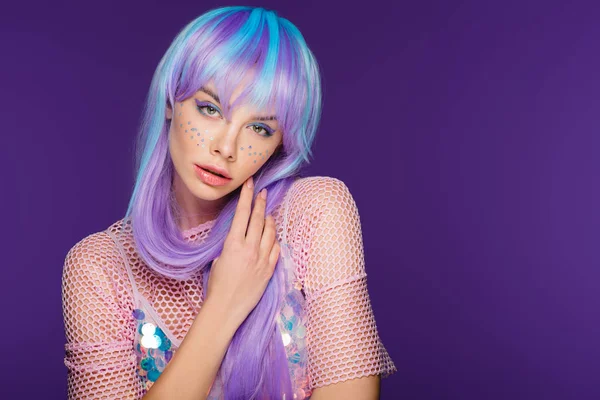 Beautiful fashionable woman posing in violet wig with stars on face, isolated on purple — Stock Photo