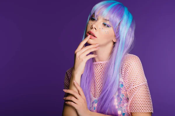 Привлекательная женщина позирует в фиолетовом парике со звездами на лице, изолированная на фиолетовом — стоковое фото