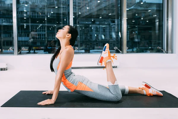 Slim asian sportswoman doing stretching exercise on fitness mat at gym — Stock Photo