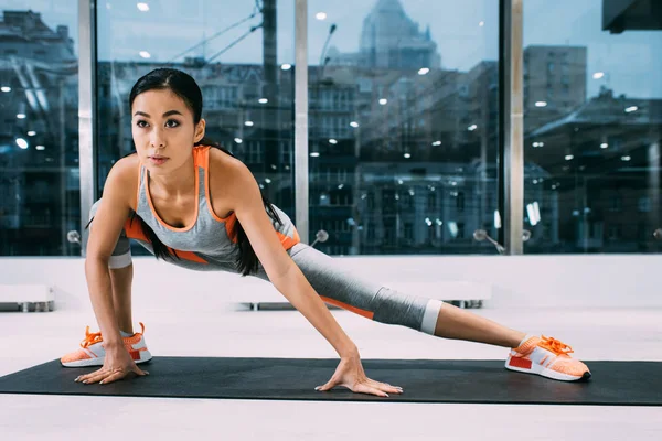 Flexible asian girl stretching leg on fitness mat at gym — Stock Photo