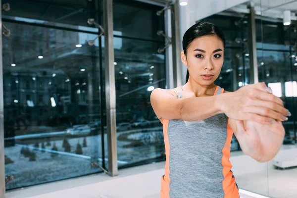 Nahaufnahme eines jungen asiatischen Mädchens, das im Fitnessstudio steht, die Hand ausstreckt und in die Kamera schaut — Stockfoto