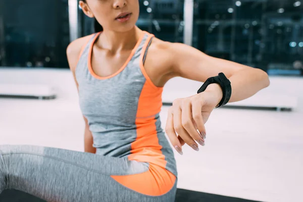 Cropped view of young girl looking fitness tracker at gym — Stock Photo