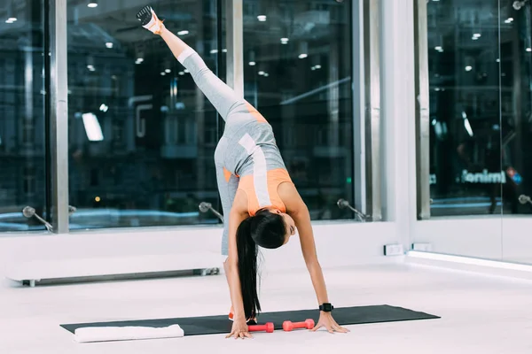 Slim girl stretching leg on fitness mat at gym — Stock Photo