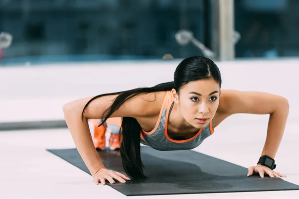 Приваблива азіатська дівчина робить прес-релізи на фітнес-маті в спортзалі — стокове фото