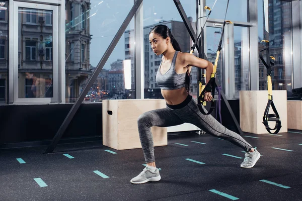 Attractive asian girl training with resistance bands at modern gym — Stock Photo