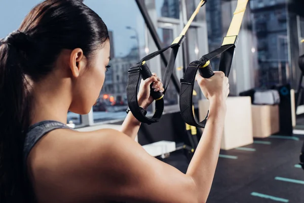 Vista posterior del entrenamiento de la deportista con bandas de resistencia en el gimnasio moderno - foto de stock