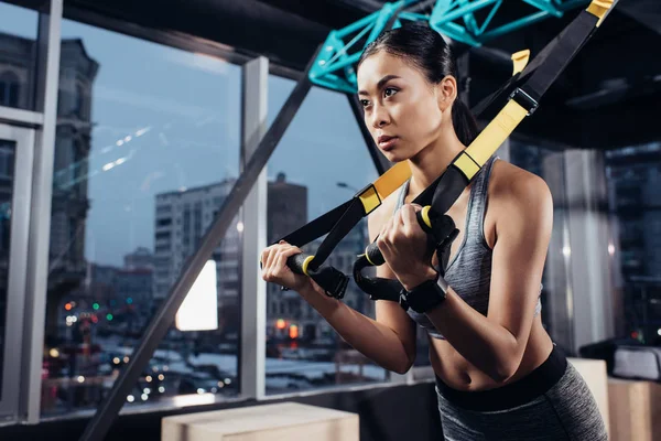 Athletic asian sportswoman training with resistance bands in fitness center — Stock Photo