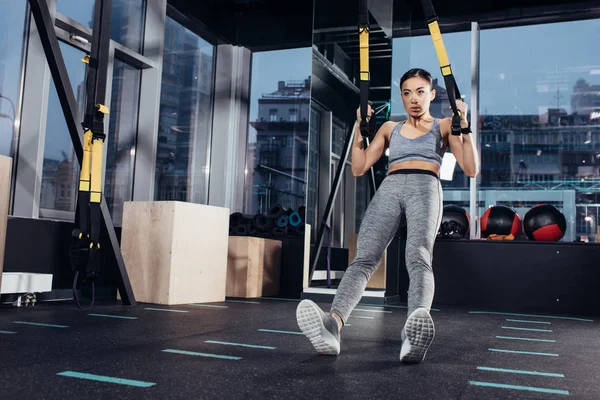 Athletic asian girl exercising  with resistance bands in sports center — Stock Photo