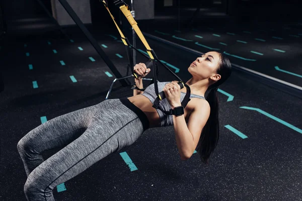 Slim asian sportswoman training with resistance bands in sports center — Stock Photo