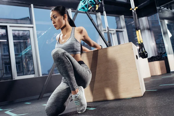 Atractiva chica asiática haciendo ejercicio con cubo de madera en el centro deportivo - foto de stock