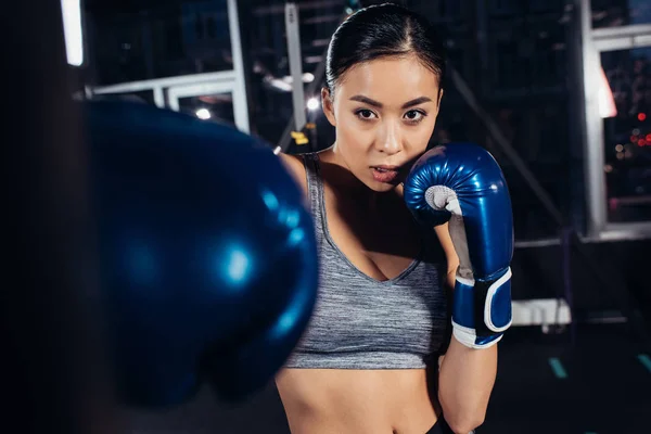 Закрытый вид на девушку в боксерских перчатках, тренирующуюся в спортзале — стоковое фото