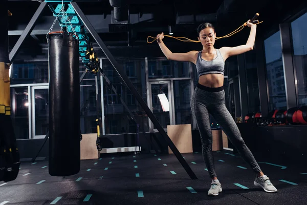Atlético asiático chica con saltar cuerda de pie en gimnasio - foto de stock
