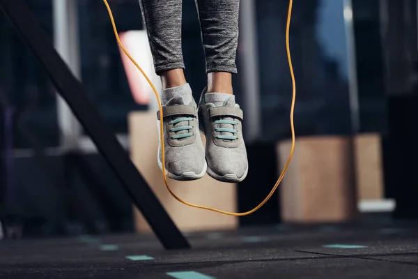 Cropped view of female legs jumping with skipping rope at gym — Stock Photo